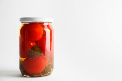 Tasty pickled tomatoes in jar on light grey background. Space for text