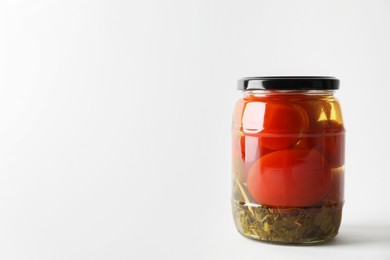 Tasty pickled tomatoes in jar on light grey background. Space for text