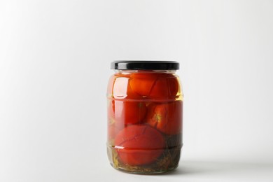 Tasty pickled tomatoes in jar on light grey background