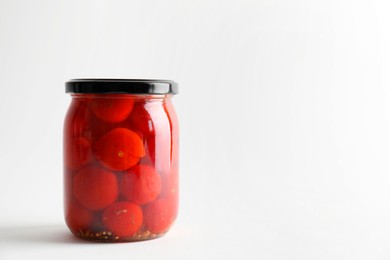 Tasty pickled tomatoes in jar on light grey background. Space for text