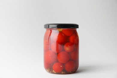 Tasty pickled tomatoes in jar on light grey background