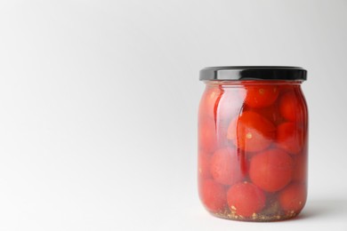 Tasty pickled tomatoes in jar on light grey background. Space for text