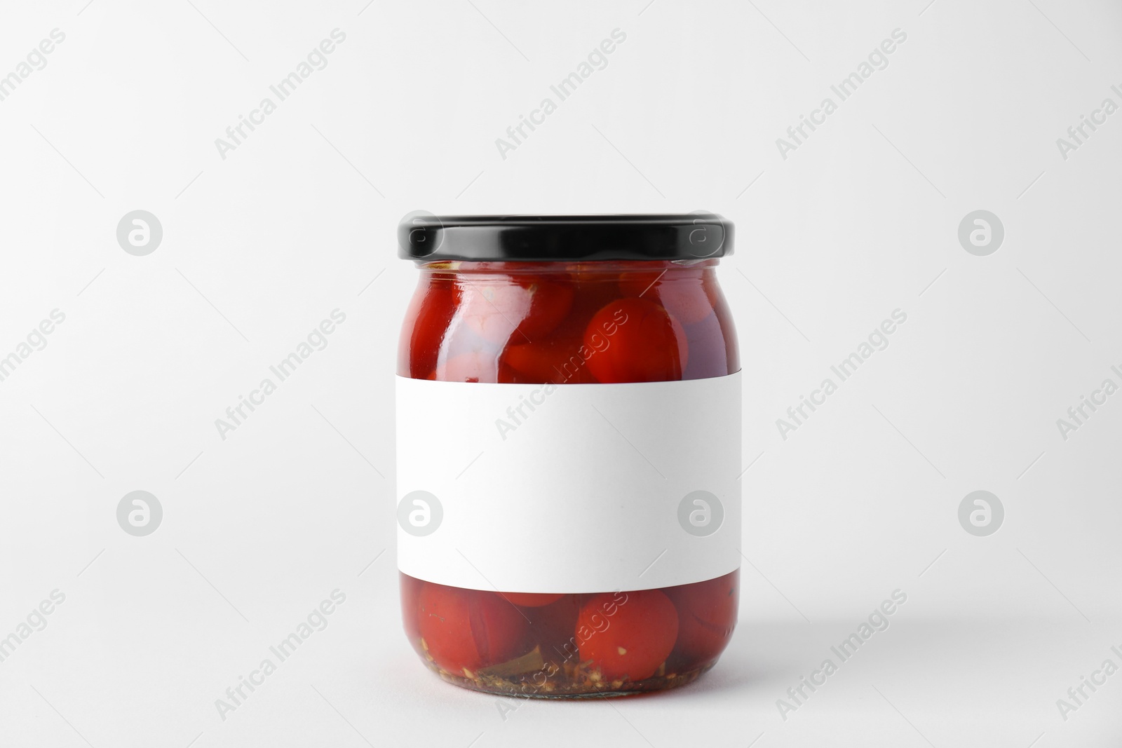 Photo of Tasty pickled tomatoes in jar on light background