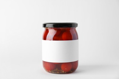 Tasty pickled tomatoes in jar on light background