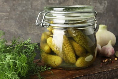 Pickled cucumbers in jar and spices on wooden table