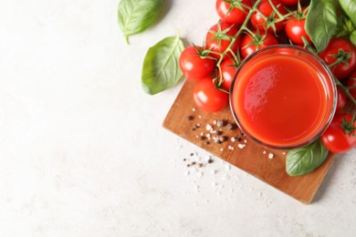 Photo of Tasty tomato juice in glass, spices and fresh vegetables on light table, flat lay. Space for text