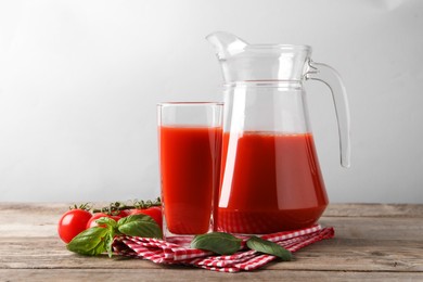 Tasty tomato juice with basil leaves and fresh vegetables on wooden table