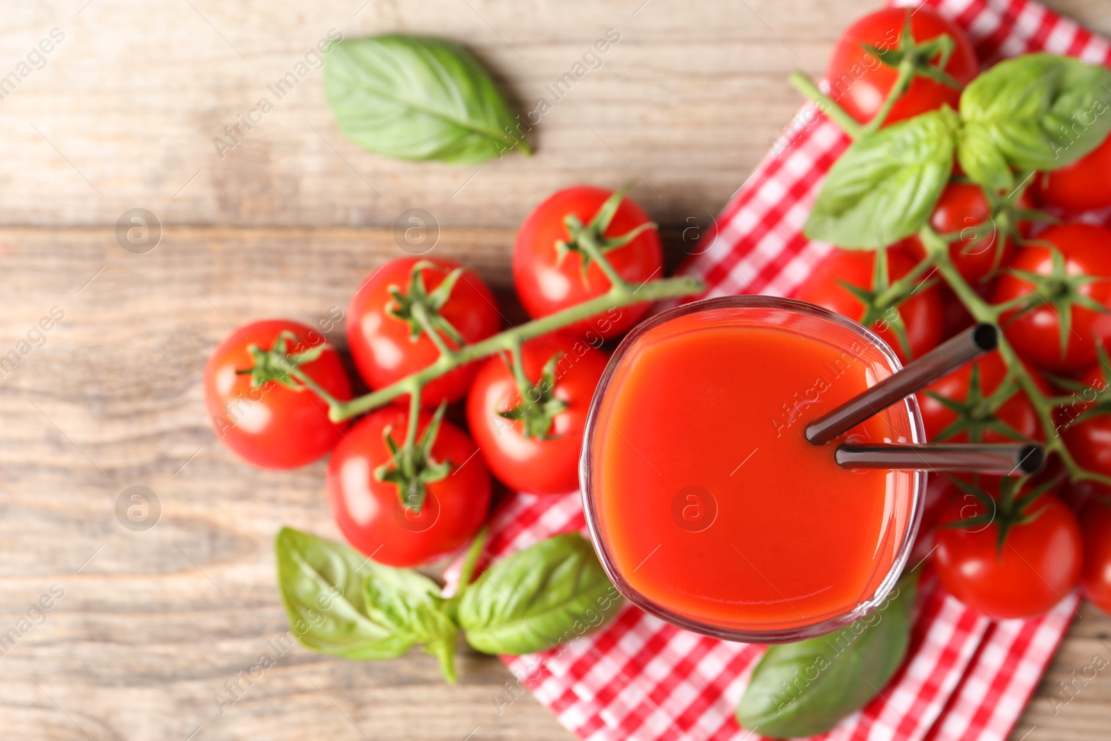 Photo of Fresh tomato juice in glass on wooden table, top view. Space for text