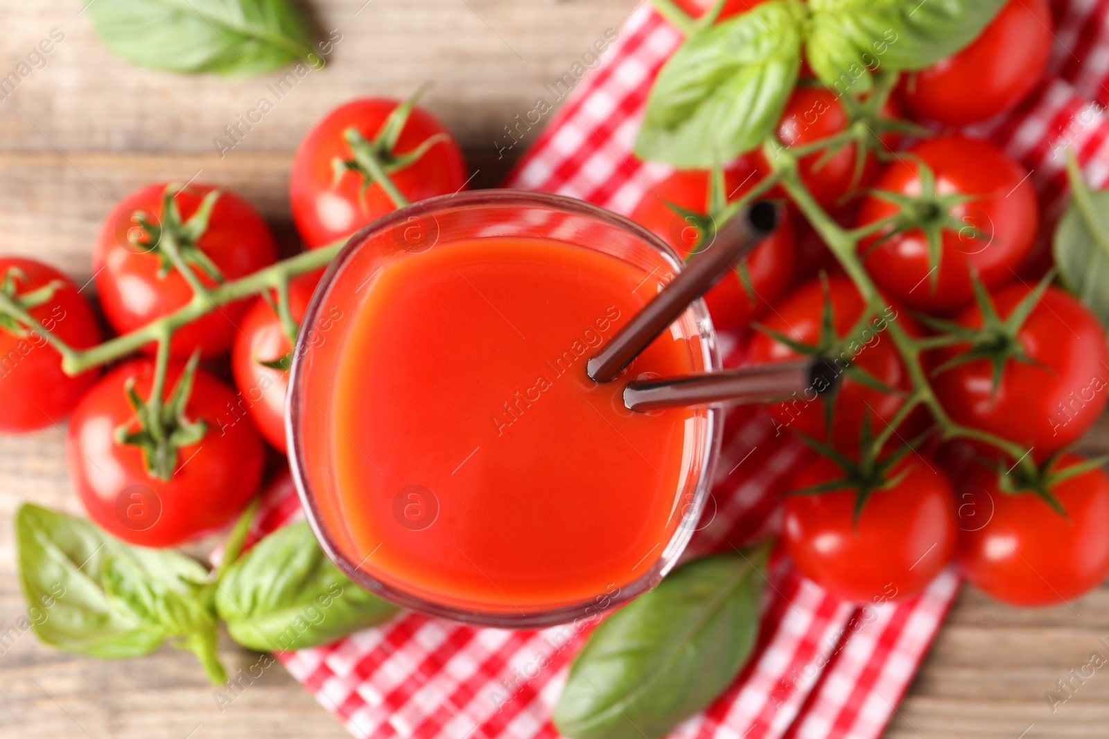 Photo of Fresh tomato juice with straws in glass on wooden table, top view