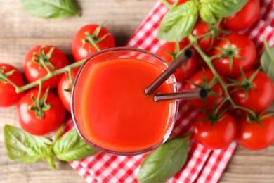 Fresh tomato juice with straws in glass on wooden table, top view