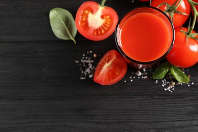 Tasty tomato juice in glass with fresh vegetables and spices on black wooden table, flat lay. Space for text