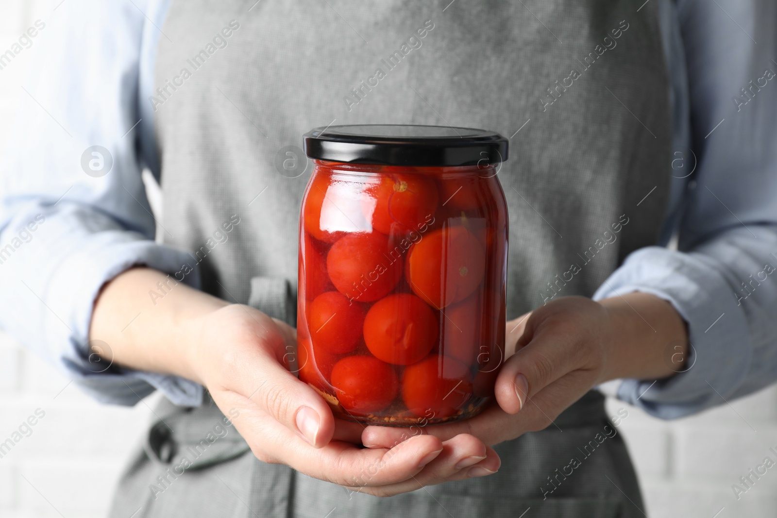 Photo of Woman holding jar with tasty pickled tomatoes, closeup