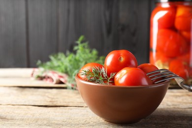 Photo of Tasty pickled tomatoes, dill and fork on wooden table, space for text