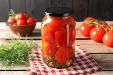 Tasty pickled tomatoes in jar, dill and fresh vegetables on wooden table