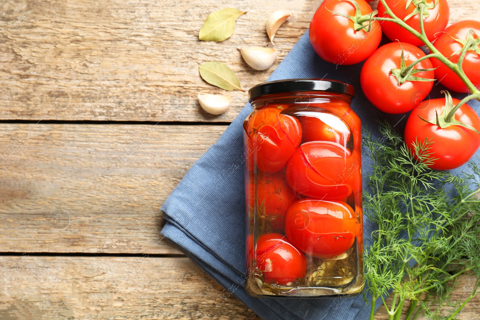 Photo of Tasty pickled tomatoes in jar, spices and fresh vegetables on wooden table, top view. Space for text