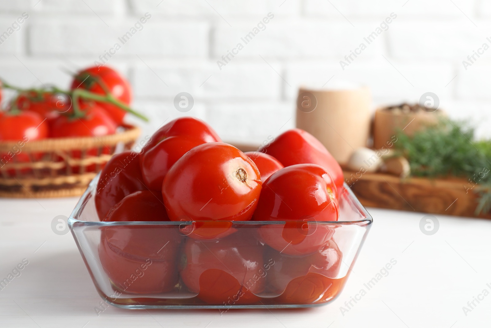 Photo of Tasty pickled tomatoes in bowl on white table