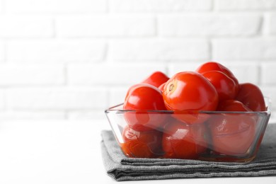 Photo of Tasty pickled tomatoes in bowl on white table, space for text