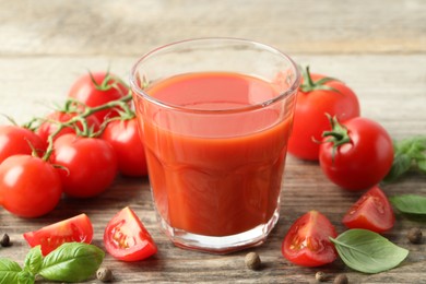 Tasty tomato juice in glass with fresh vegetables and spices on wooden table, closeup