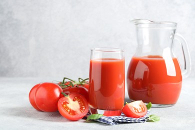 Photo of Tasty tomato juice with fresh vegetables and basil leaves on light grey table