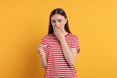 Photo of Shocked woman holding pregnancy test on orange background