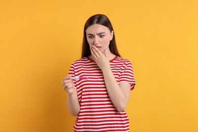 Shocked woman holding pregnancy test on orange background