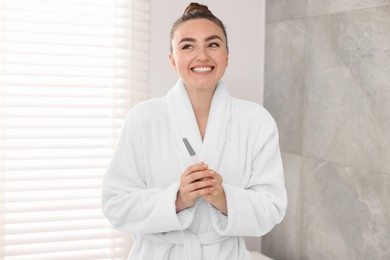 Happy woman holding pregnancy test in bathroom