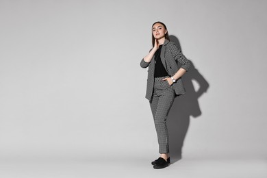 Photo of Beautiful woman in stylish suit on gray background