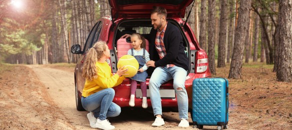 Family with suitcases and car in forest on sunny morning. Banner design