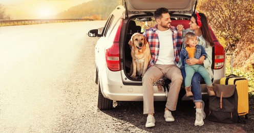 Parents, their daughter and dog sitting in car trunk near road. Banner design with space for text