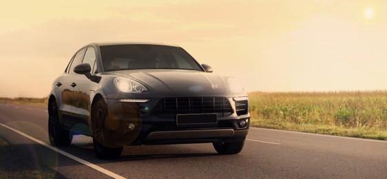 Image of Modern black car on asphalt road outdoors. Banner design