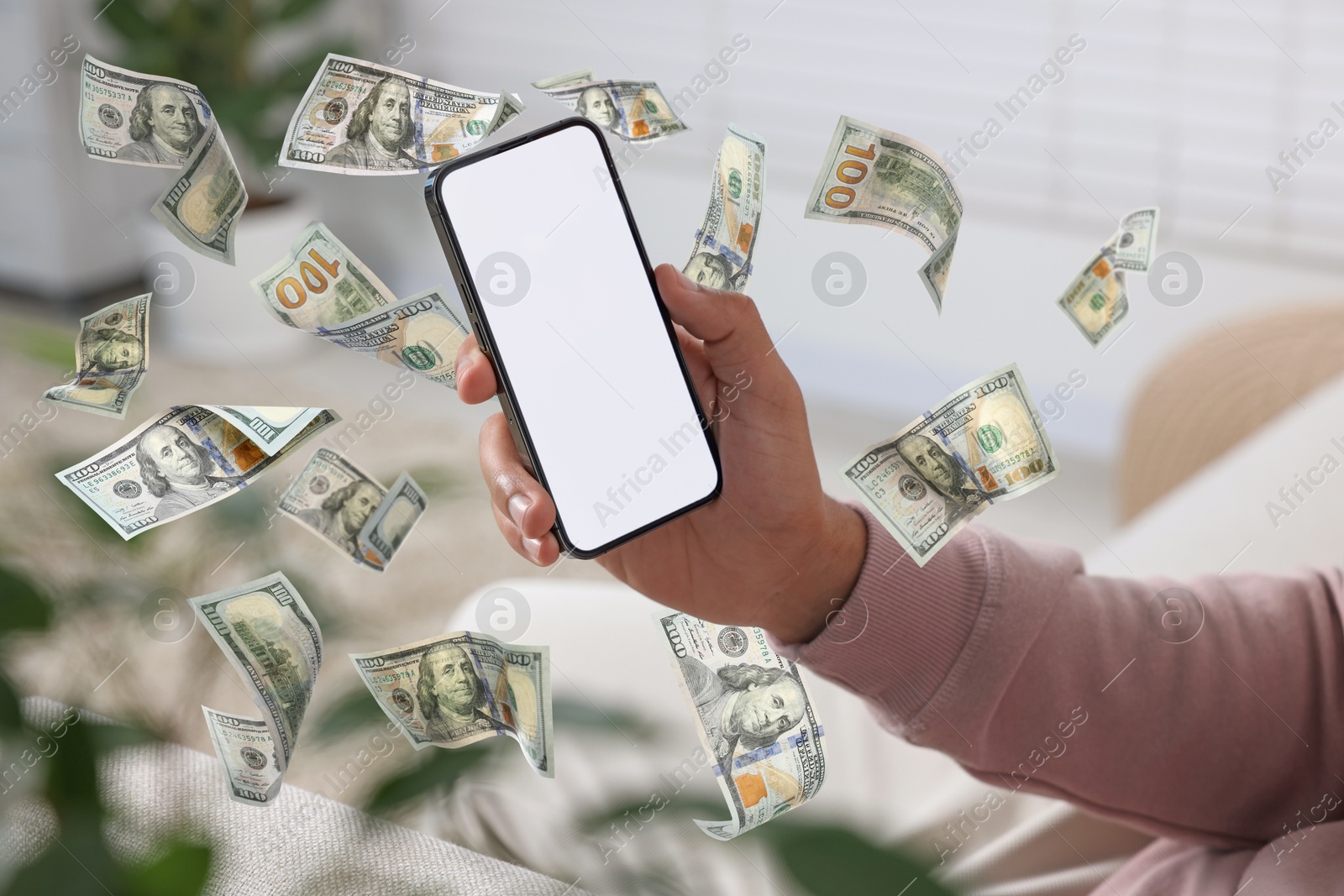 Image of Man using smartphone at home, closeup. Money flying around device