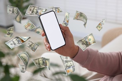 Man using smartphone at home, closeup. Money flying around device