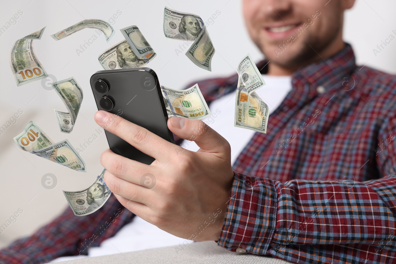 Image of Man using smartphone at home, closeup. Money flying around device