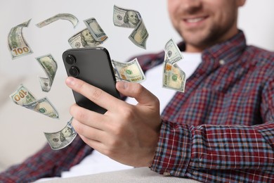 Image of Man using smartphone at home, closeup. Money flying around device