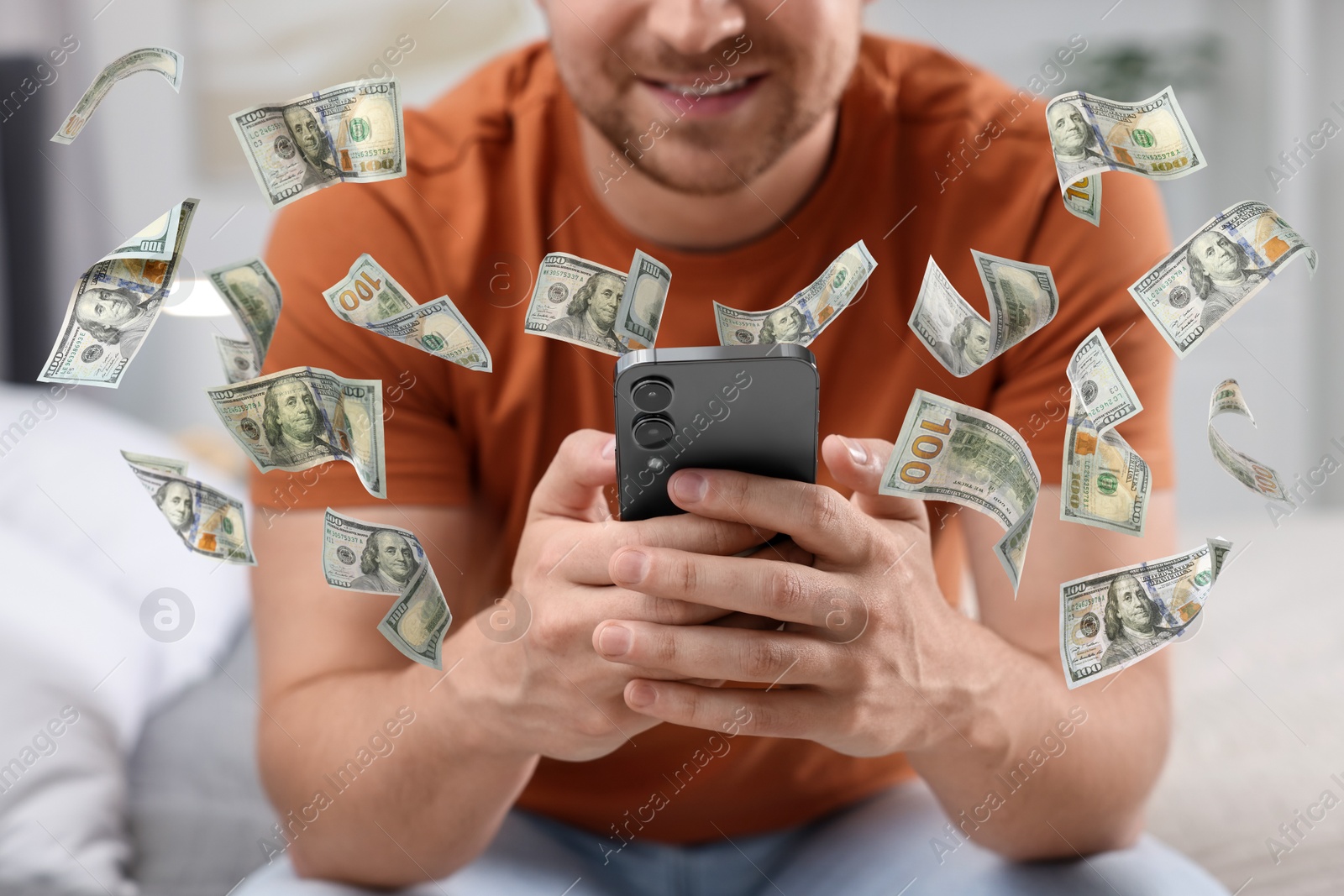 Image of Man using smartphone at home, closeup. Money flying around device