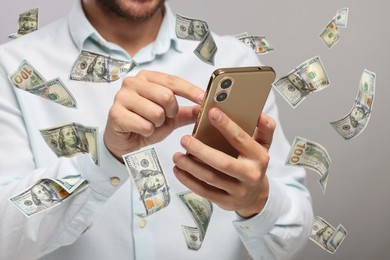 Image of Man using smartphone on light background, closeup. Money flying around device