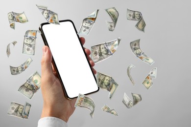 Image of Man showing smartphone with blank screen on light grey background, closeup. Money flying around device