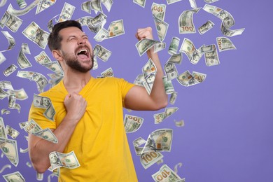 Happy man under money rain on violet background