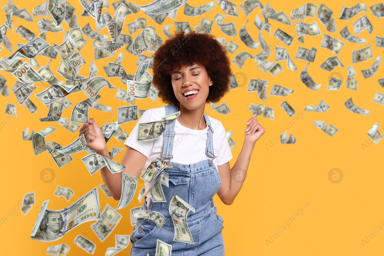 Image of Happy woman under money rain on orange background