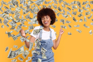 Happy woman under money rain on orange background