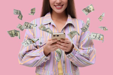 Image of Woman using smartphone on pink background, closeup. Money flying around device