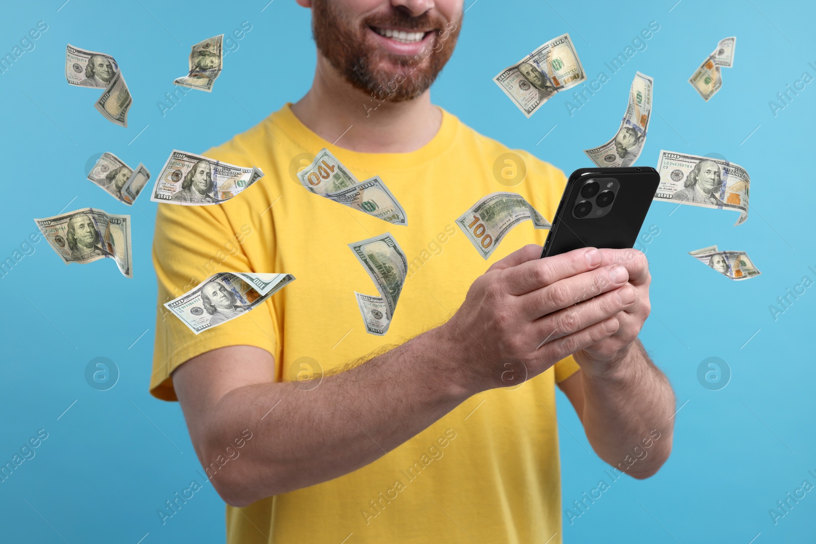 Image of Man using smartphone on light blue background, closeup. Money flying around device