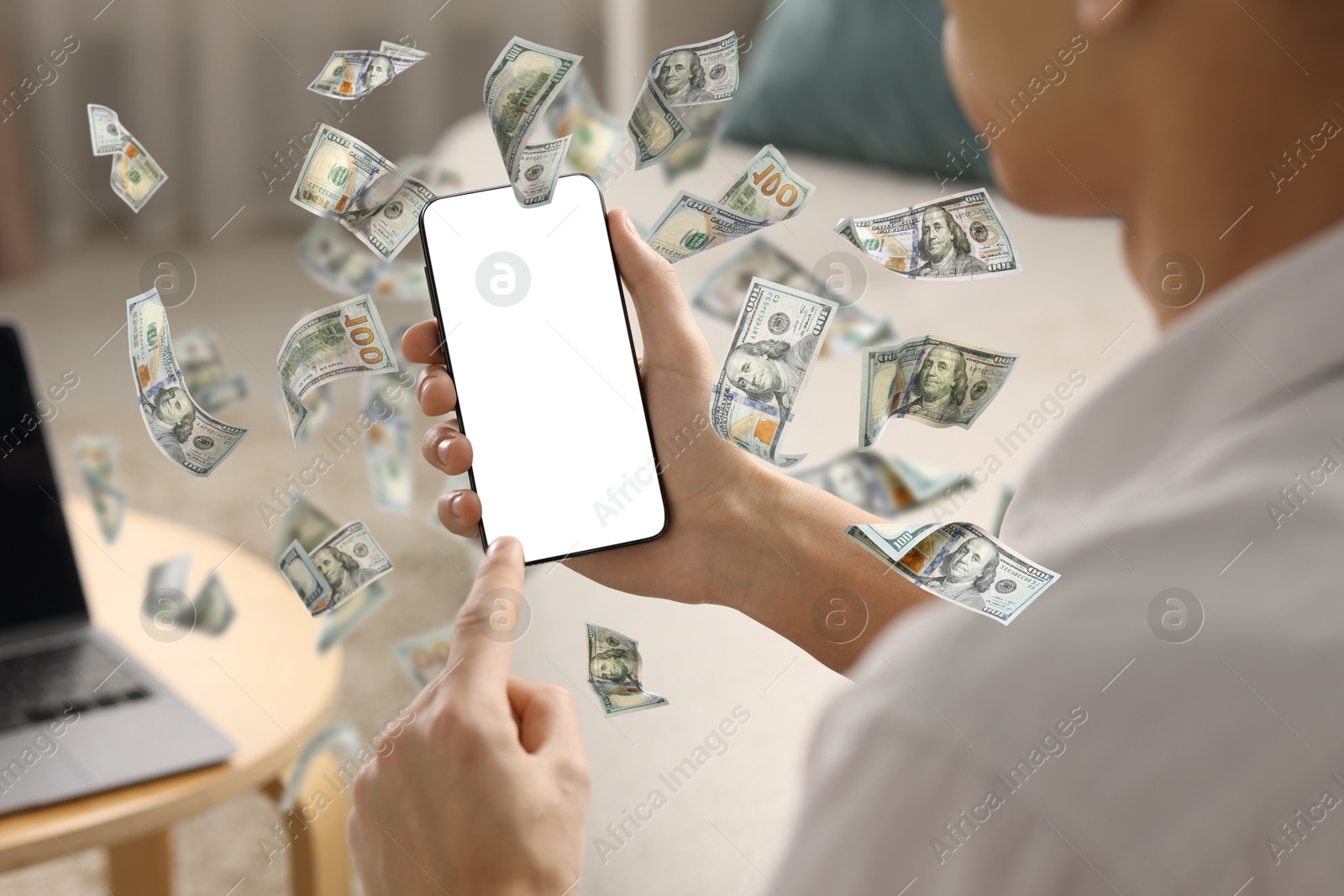 Image of Man using smartphone at home, closeup. Money flying around device