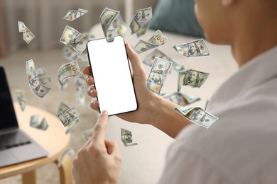 Image of Man using smartphone at home, closeup. Money flying around device