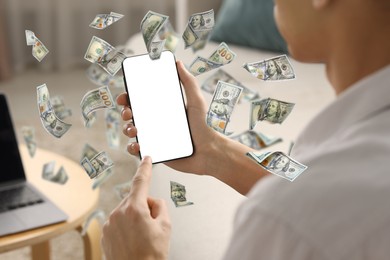 Man using smartphone at home, closeup. Money flying around device