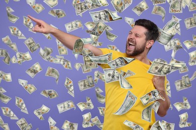 Happy man under money rain on violet background