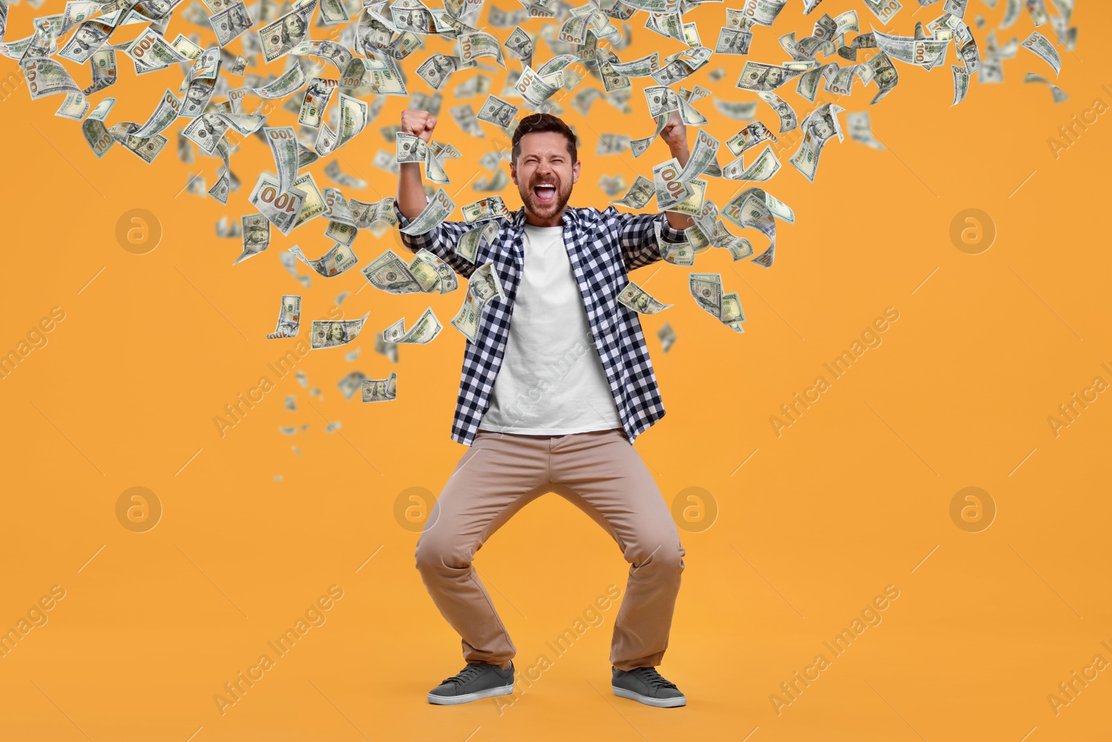 Image of Happy man under money rain on orange background