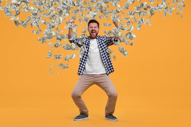 Image of Happy man under money rain on orange background