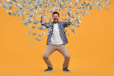 Happy man under money rain on orange background