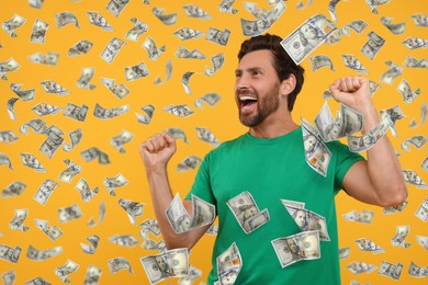 Happy man under money rain on orange background